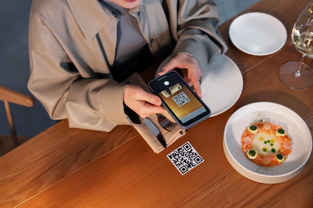 Customer scanning QR code at restaurant table with beautifully plated dish